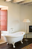Freistehende Vintage Badewanne und klassische Stehlampe in Zimmerecke mit rustikalem Flair