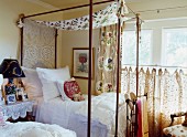 Delicate four-poster bed next to window in country-style bedroom