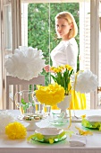 A woman looking at a table laid for Easter celebrations, with narcissi and pompoms