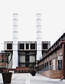 Planters of cacti in courtyard of former factory with tall chimneys