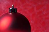 Red Christmas tree ball in front of a red background