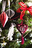 Heart-shaped decoration embroidered with the word Noel hanging on Christmas tree decorated in red and white