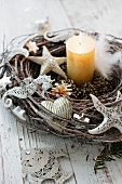 Willow wreath with ornaments shaped like marine animals and lit candle