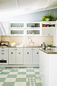 Modern kitchen with stainless steel worksurfaces; tiled splashback and cup handles on base units lend a vintage atmosphere