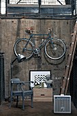 Armchair, retro lamp, picture and bust of a woman below bicycle hanging on cellar wall