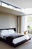 Dunkles Bettgestell in minimalistischem Schlafzimmer