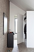 Cubic washstand against modern brick wall opposite wardrobe under sloping roof