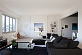 Moderne, graue Sofakombination und rollbarer Couchtisch mit Glasplatte in grossräumigem, modernem Wohnzimmer