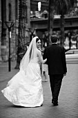 Braut in langem weißem Kleid neben Bräutigam in schwarzem Anzug auf der Straße (s-w-Aufnahme)