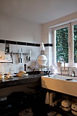 Modern kitchen with black stone worksurface and trough-style sink with vintage tap fittings below window