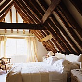 Attic bedroom with exposed, rustic wooden roof structure
