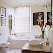 Vase of flowers on modern washstand and artworks on walls in bright bathroom