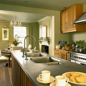Country home style kitchen with pastel green walls, wooden cabinets, open fireplace and dining area
