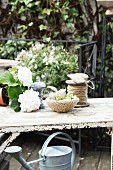 White hydrangea next to dish with hand-knitted cover and reel of yarn on vintage garden table