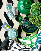 Arrangement of various ceramic pots, green ornaments and photos on black and white rug