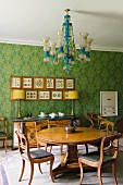 Dining area with antique, English furniture, chandelier & floral patterned wallpaper