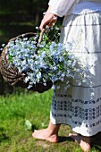 A woman holding a basket with forget-me-nots