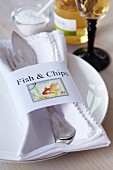 Napkin ring with lettering reading Fish & Chips and decorated with postage stamps