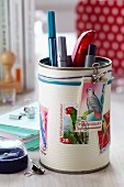Tin can decorated with postage stamps with bird motifs used as pen holder