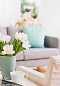 Bouquet of tulips on table next to armchair in living room