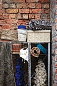 Woven baskets and knitted, ruched scarves in metal shelving units against rustic brick wall