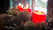 Adventsgesteck mit brennenden Kerzen