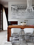weiße Schalenstühle um Holztisch unter Designer Hängeleuchte, an Wand Gemälde mit Abendmahlmotiv in schwarz-weiß
