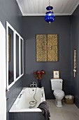Black-painted and partially tiled bathroom with bathtub, toilet & framed mirror