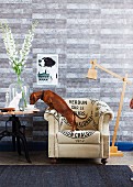 Dog standing on white armchair with lettering motif drinking out of cup