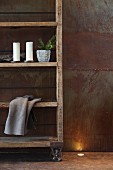 Vintage-style, wooden shelves on castors against corten steel wall