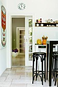 Bentwood stools at kitchen counter on limestone flags; view through half-open sliding door