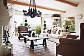 Armchairs and sofa around rustic wooden table on terracotta floor in country-style living room