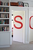 Von Einbauregalen umrahmte Zimmertüren, verziert mit roten Buchstaben