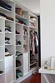 Walk-in wardrobe with clothes in compartments and drawers