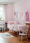 Children's room in pink with metal bed and wooden desk