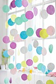 Strings of coloured round discs hanging in front of window