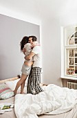 Couple in pyjamas standing on bed embracing