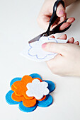 Flowers cut from felt in various colours; woman cutting out a flower template