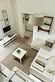 Blick von oben auf Loungebereich mit hellen Polstermöbeln auf Teppich und Dielenboden in modernem Ambiente