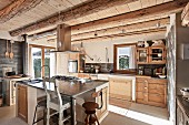 Island counter and vintage kitchen chairs in rustic fitted kitchen of wooden chalet