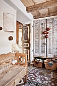 Hallway with rustic wooden bench on patterned tiled floor and vintage-style interior shutters