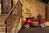Red Vespa Scooter Parked by a Stone Wall