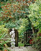 Blick in Garten mit Statue neben geöffnetem Gartentor