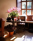 Sitzecke vor Sprossenfenster mit Bank & Blumenarrangement auf rundem Holztisch