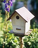 Vogelhäuschen aus Holz auf Ständer im Garten