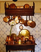 Kupfertöpfe & Kupferpfannen in Regal & auf Holztischchen vor gefliester Küchenwand