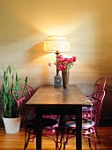 Rustikaler Holztisch und pinkfarbene Metallstühle an Esszimmerwand