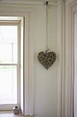 Decorative heart hanging in corner of room next to window