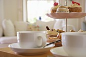 Cup of tea & pastries on cake stand on table in living room (close-up)