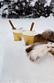 Hot apple punch with pear liqueur next to fur in snow